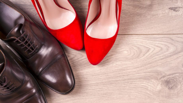 Image of a pair of men's brown business shoes next to a pair of bright red high heels