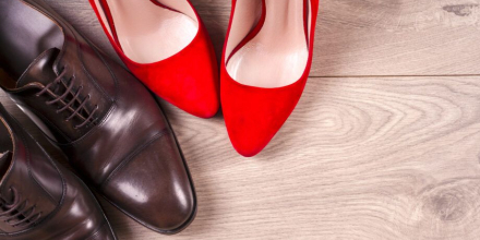 Image of a pair of men's brown business shoes next to a pair of bright red high heels