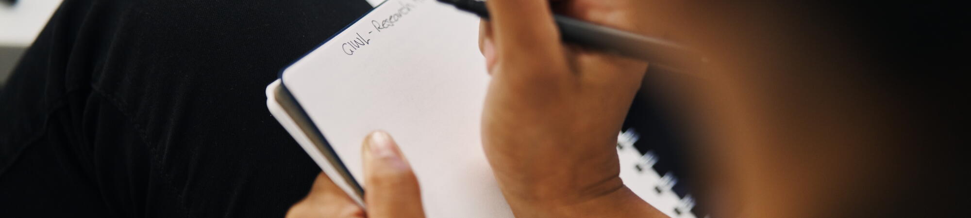 A person holding pen and note